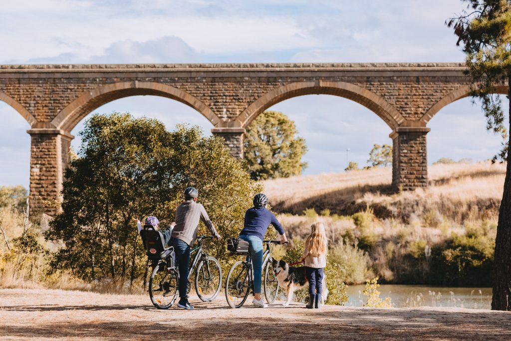 Family on bikes looking at Malmsbury Bluestone Viaduct Bridge